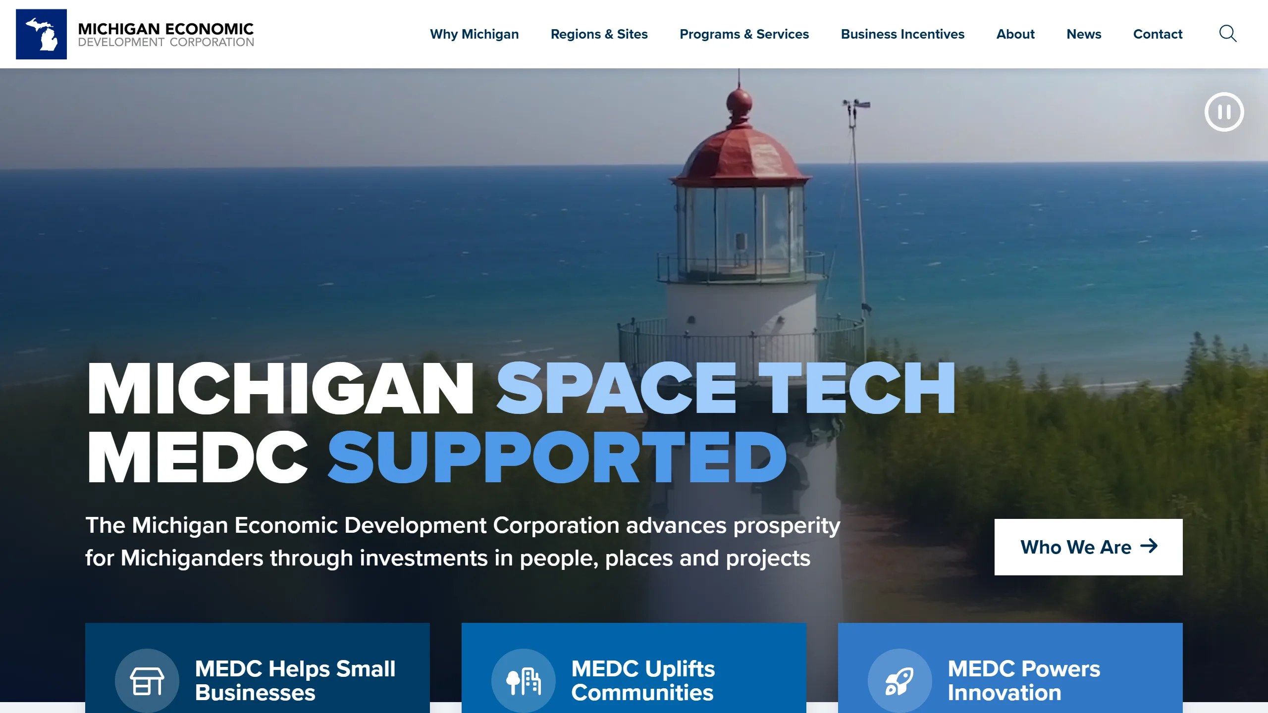 Michigan Business homepage: a video hero of a lighthouse on Lake Michigan with a bold headline, a Who We Are button, and blue call-to-action cards below.